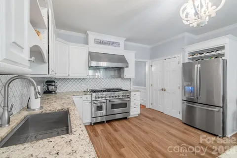 a kitchen with granite countertop a refrigerator stove and sink
