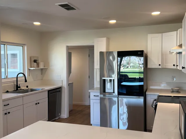 a kitchen with stainless steel appliances kitchen island granite countertop a refrigerator a sink a stove and island