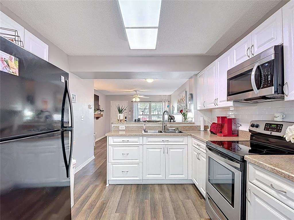 7828 Hardwick Drive, Unit 916 New Port Richey, FL 34653 - Photo 13 of 40 a kitchen with stainless steel appliances granite countertop a sink dishwasher a refrigerator and white cabinets with wooden floor