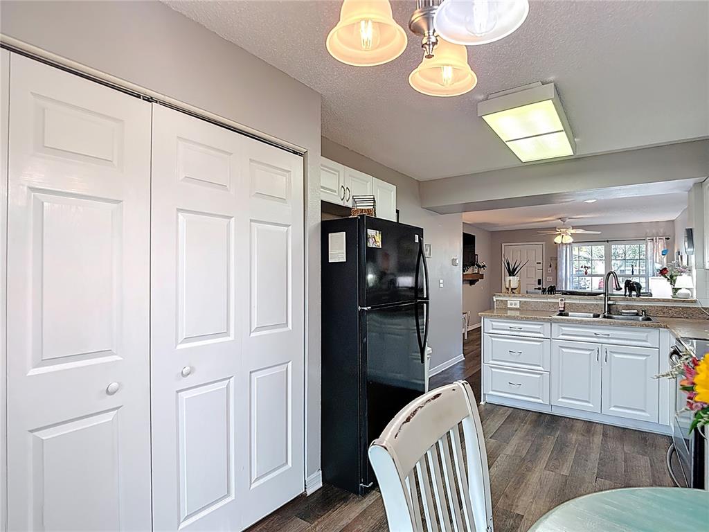 7828 Hardwick Drive, Unit 916 New Port Richey, FL 34653 - Photo 17 of 40 a kitchen with stainless steel appliances granite countertop a refrigerator a stove a dining table and chairs with wooden floor