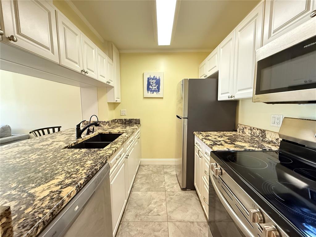 12200 Vonn Road, Unit 2105 Largo, FL 33774 - Photo 17 of 37 a kitchen with stainless steel appliances granite countertop a stove a sink and a refrigerator