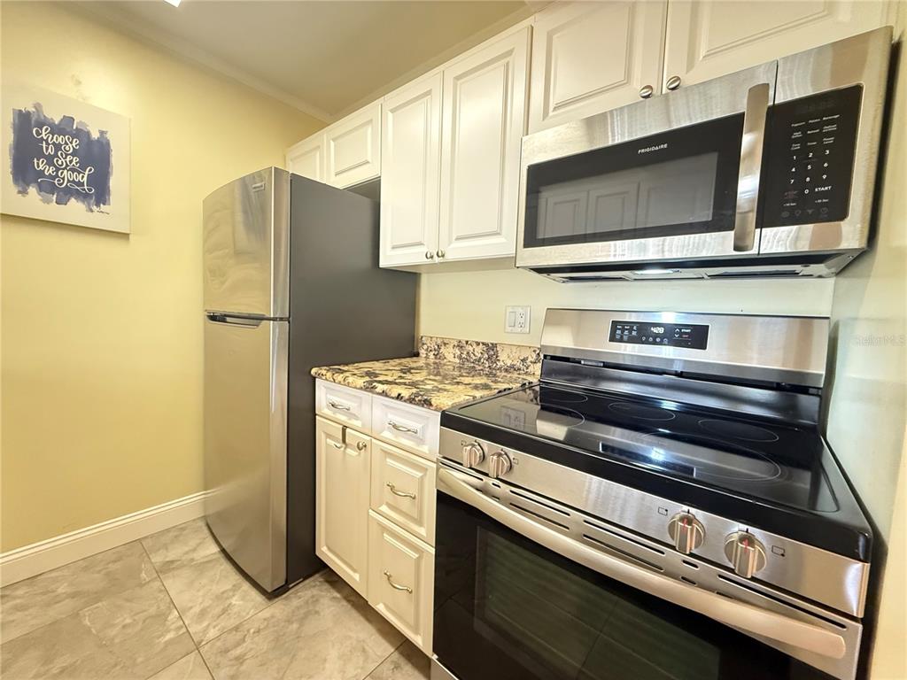 12200 Vonn Road, Unit 2105 Largo, FL 33774 - Photo 19 of 37 a kitchen with stainless steel appliances a refrigerator a stove a microwave and cabinets