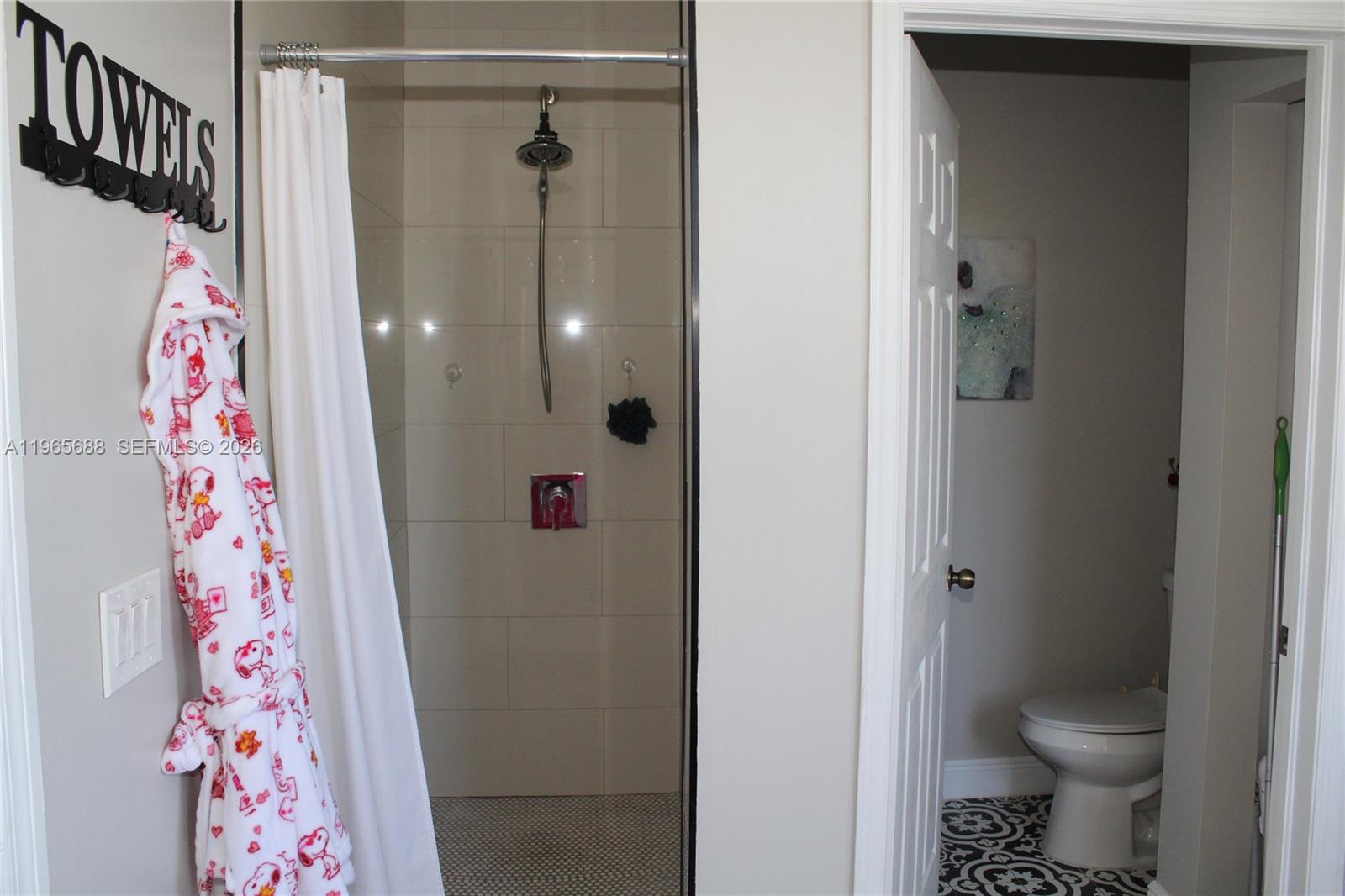 20135 Southwest 129th Avenue Miami, FL 33177 - Photo 16 of 54 a bathroom with a shower curtain and a toilet