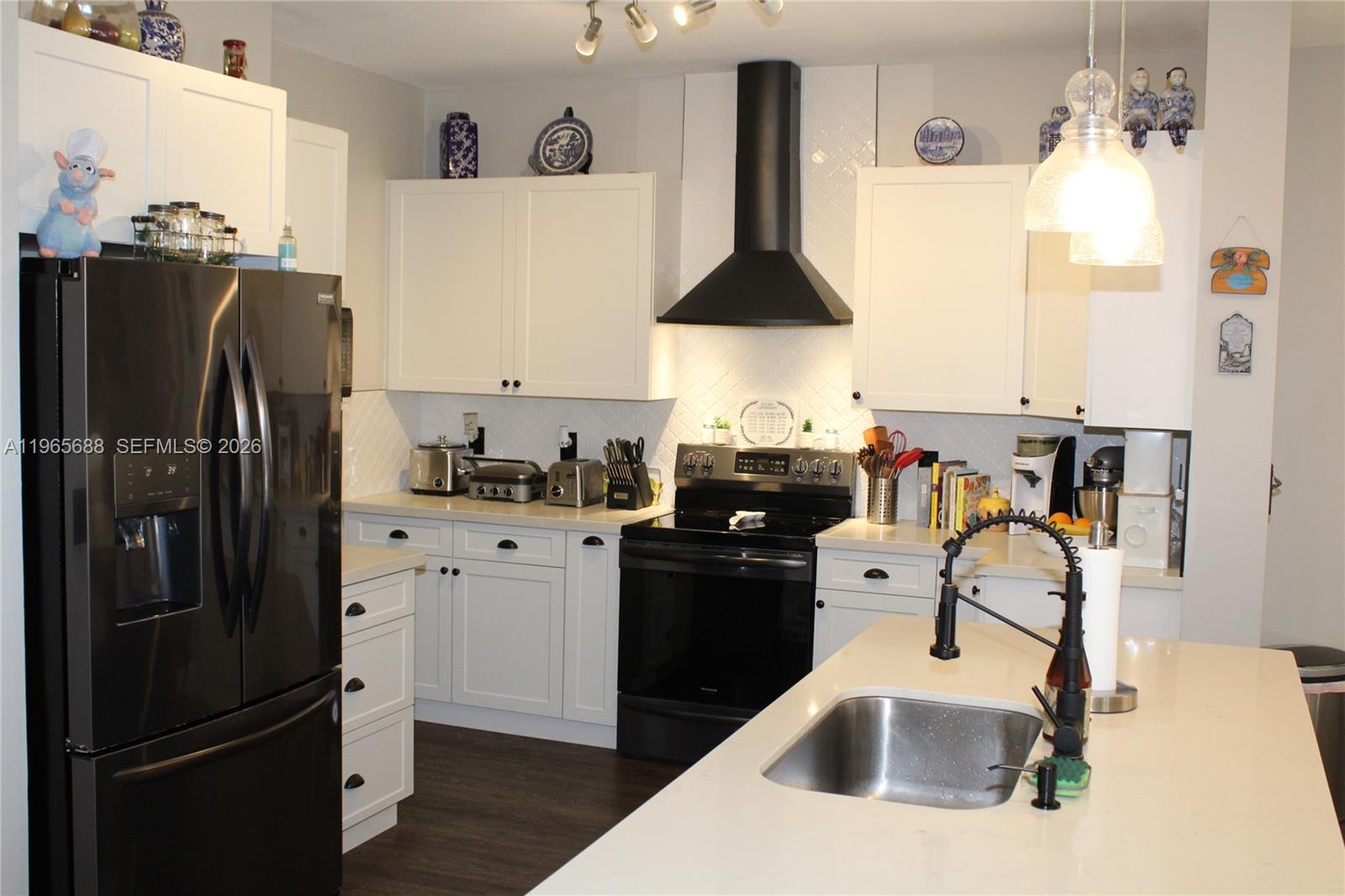 20135 Southwest 129th Avenue Miami, FL 33177 - Photo 41 of 54 a kitchen with stainless steel appliances granite countertop a refrigerator a stove and a sink with wooden floor