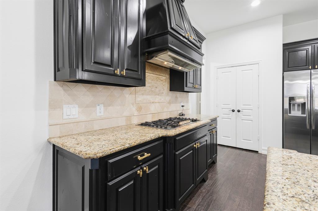 1995 Verde Court Allen, TX 75013 - Photo 19 of 30 Kitchen featuring granite countertops, dark wood cabinetry, a built-in gas range, stainless steel refrigerator, and wood-finish flooring