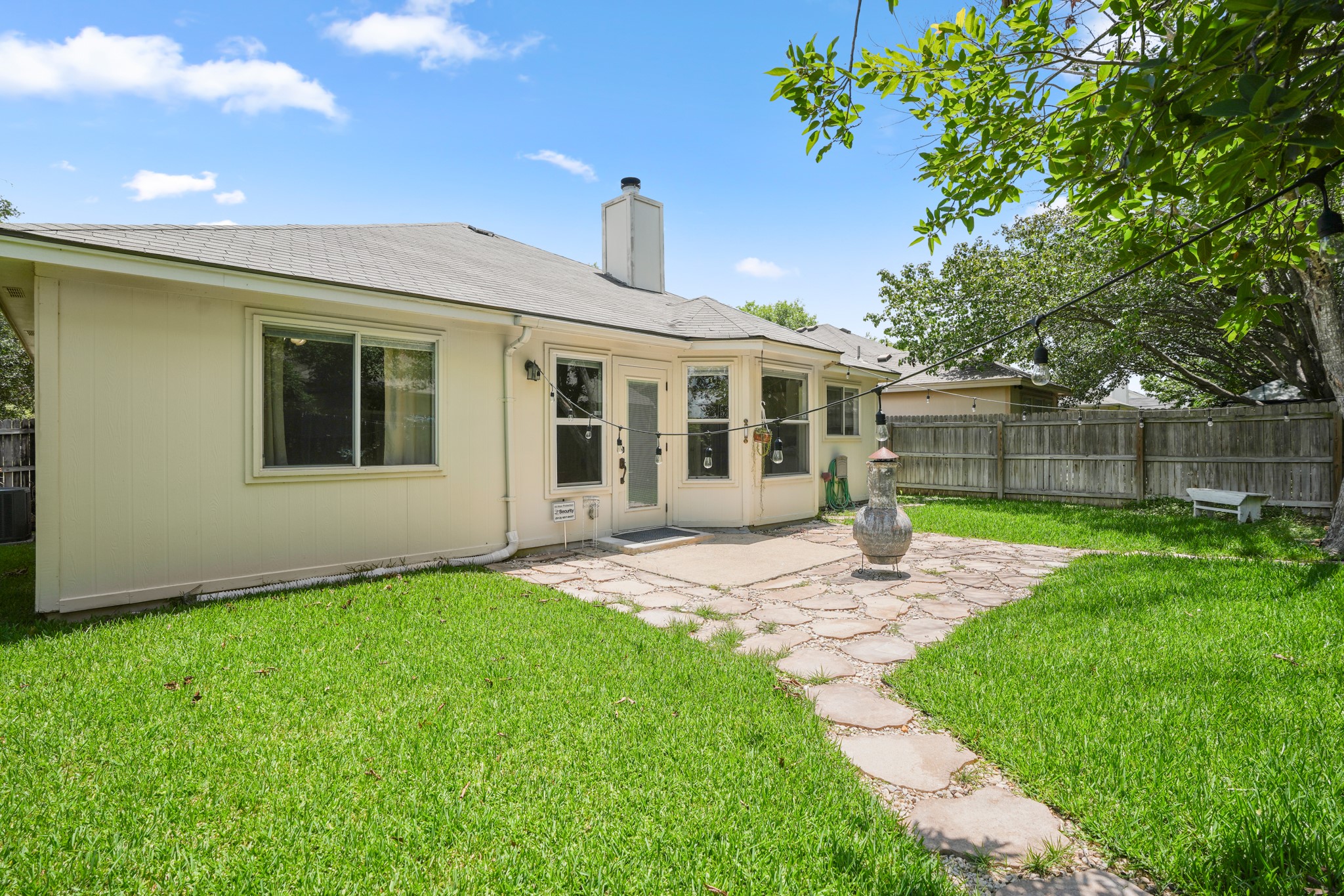 438 Katy Crossing Georgetown, TX 78626 - Photo 21 of 24 A sprawling backyard features a large stone patio, stepping stones, and a wooden privacy fence.