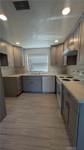 a large kitchen with stainless steel appliances a stove a sink and a refrigerator