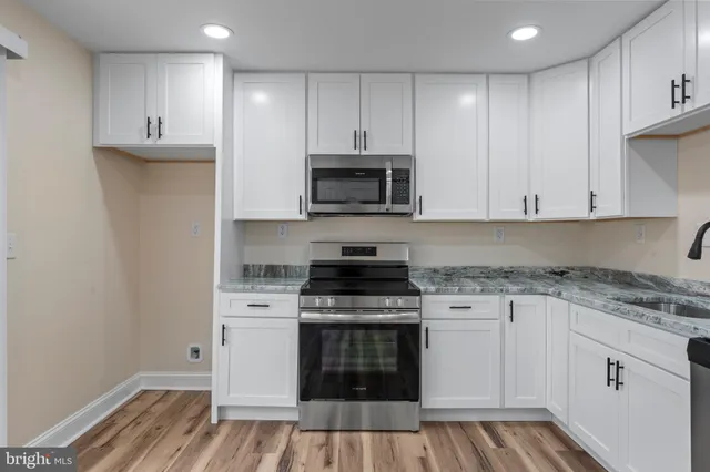 a kitchen with granite countertop white cabinets and stainless steel appliances