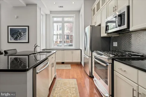 a kitchen with stainless steel appliances granite countertop a refrigerator and a stove top oven
