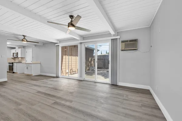 a view of an empty room with wooden floor and a ceiling fan