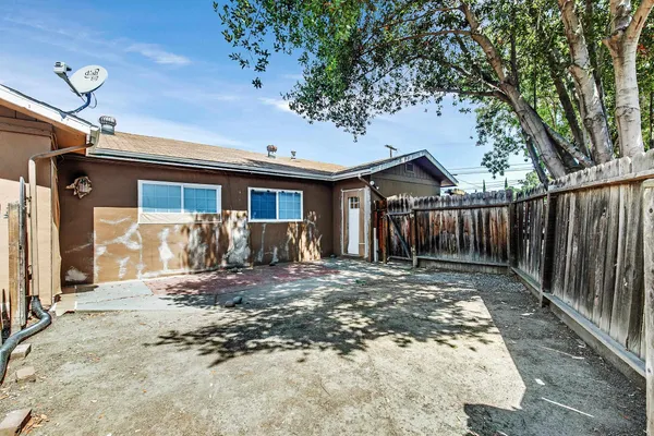 a view of a house with wooden fence next to a yard