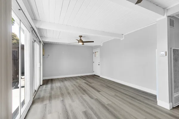 a view of an empty room with wooden floor and a window