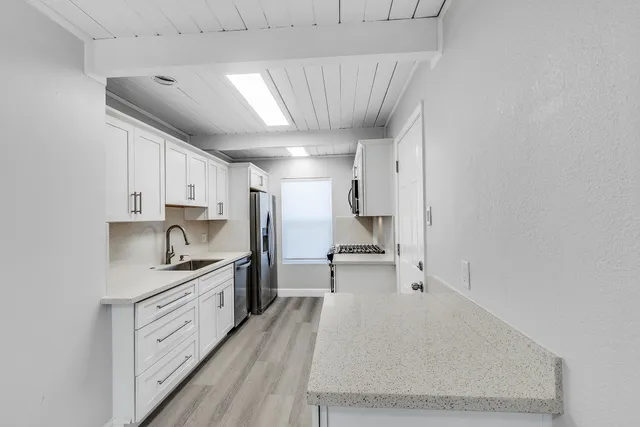 a large kitchen with a stove a sink dishwasher and a refrigerator with wooden floor