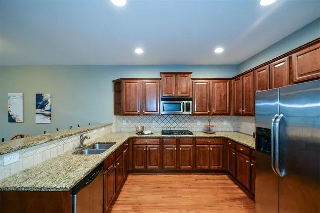 a kitchen with stainless steel appliances a refrigerator and a wooden floor