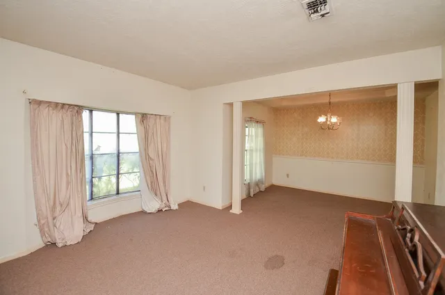 en empty room with windows and chandelier