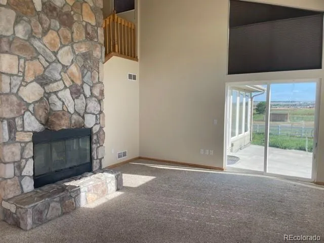 a view of an empty room with wooden floor and a fireplace