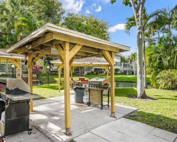 a view of a park with table and chairs under an umbrella