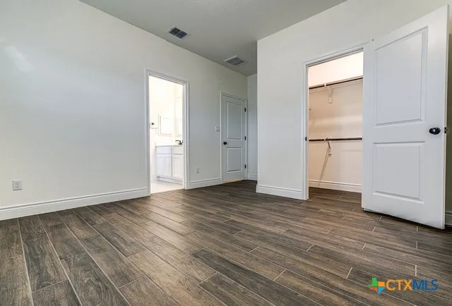 a view of an empty room with chandelier fan and wooden floor