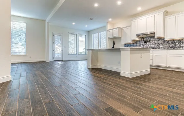 a view of kitchen with granite countertop white cabinets and wooden floor