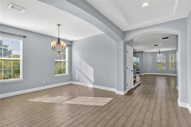 a view of an empty room with window and wooden floor