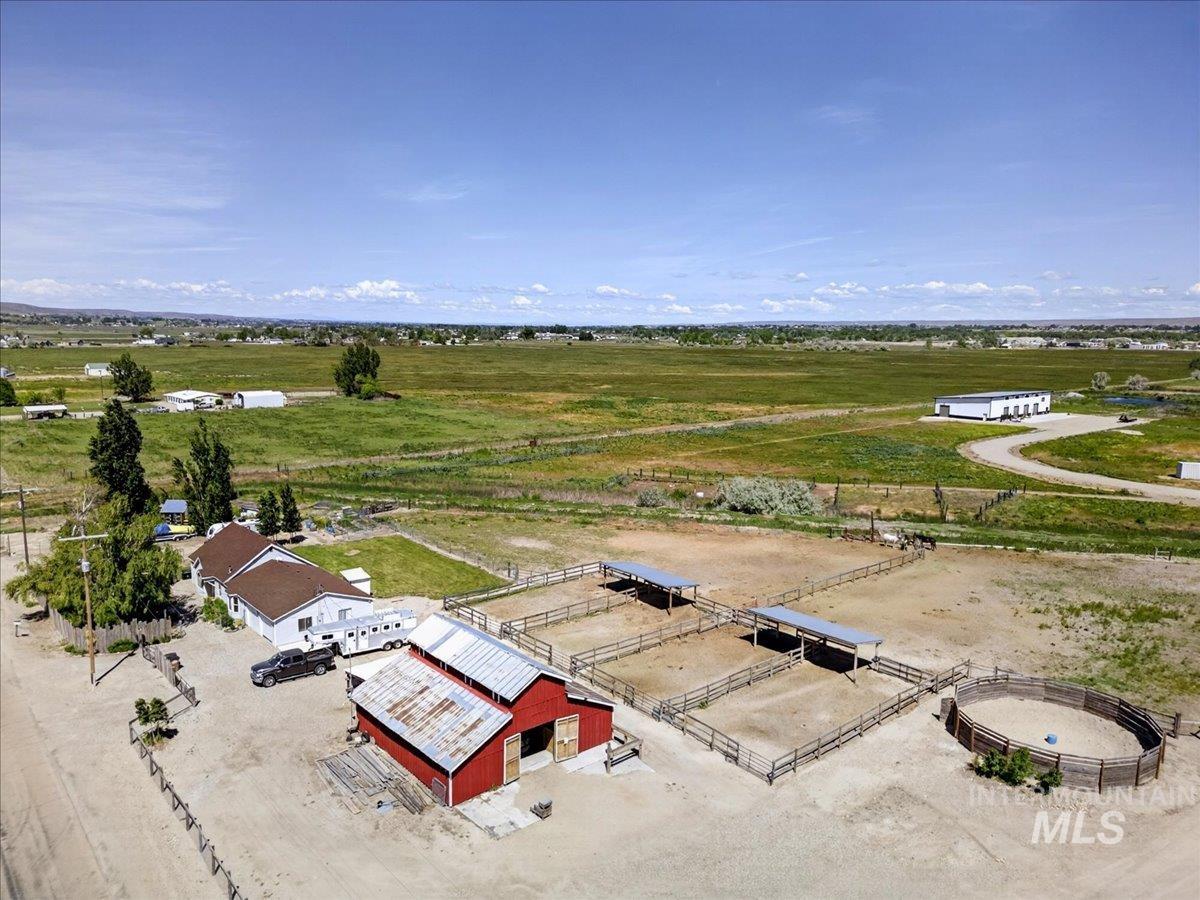 2588 West Sales Yard Road Emmett, ID 83617 - Photo 6 of 49 Expansive rural property featuring a red barn with a metal roof, multiple fenced enclosures, covered shelters within the enclosures, and a round pen