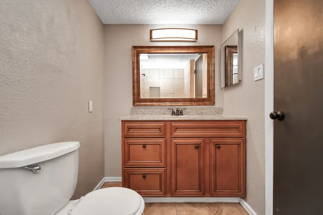 a bathroom with a granite countertop toilet sink and mirror