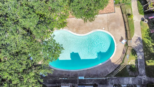 an aerial view of a house with swimming pool and trees