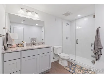 a bathroom with a granite countertop sink a toilet a mirror and shower
