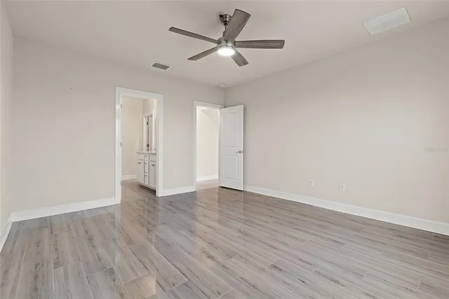 an empty room with wooden floor and ceiling fan