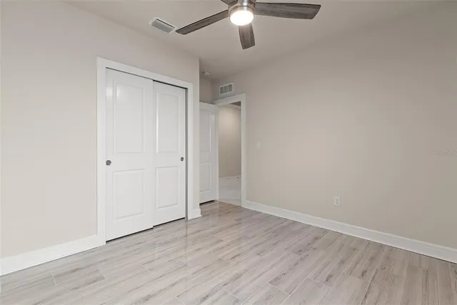 an empty room with wooden floor fan and window