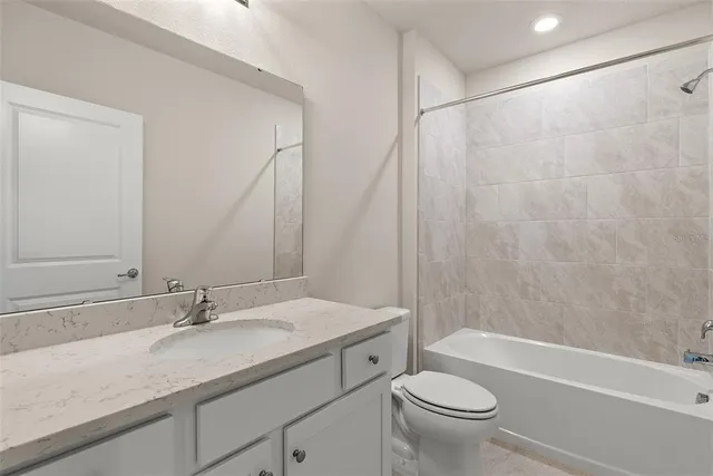 a bathroom with a granite countertop sink a toilet and a bathtub
