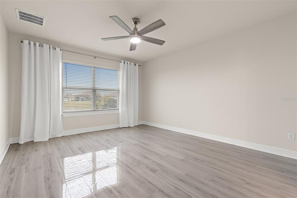 9256 Royal River Circle Parrish, FL 34219 - Photo 7 of 38 an empty room with wooden floor chandelier fan and windows