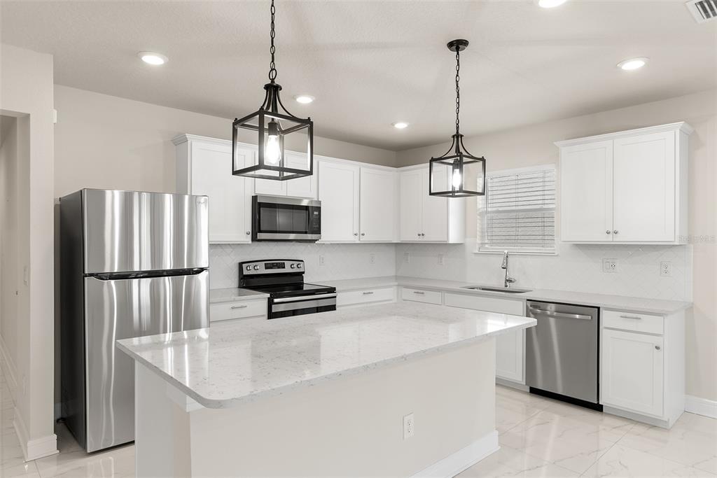 9256 Royal River Circle Parrish, FL 34219 - Photo 9 of 38 a kitchen with stainless steel appliances granite countertop a refrigerator a sink dishwasher a oven a dining table and chairs with wooden floors