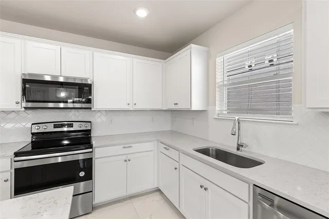 a kitchen with white cabinets appliances and a sink
