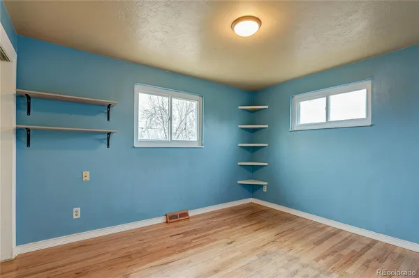 an empty room with wooden floor closet and windows