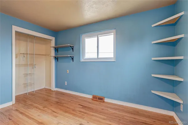 a view of empty room with wooden floor and fan