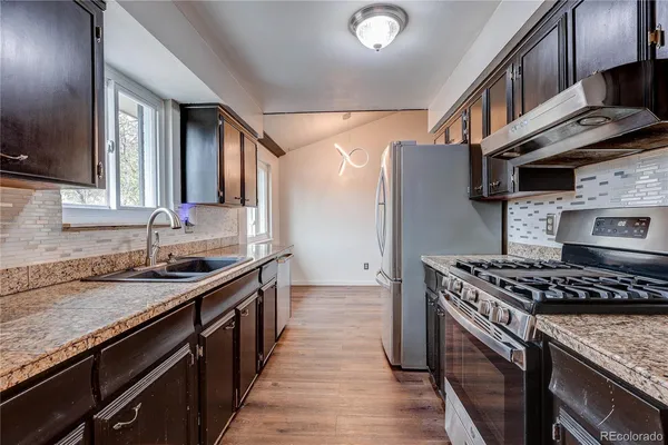 a kitchen with granite countertop a sink stove and cabinets