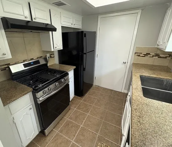 a kitchen with stainless steel appliances granite countertop a sink and a white cabinets
