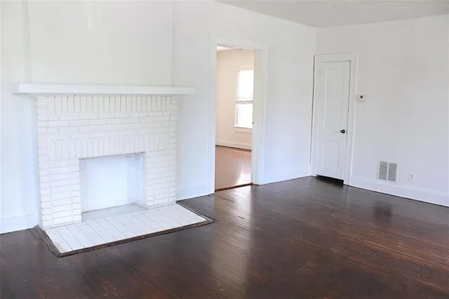 an empty room with wooden floor and fireplace