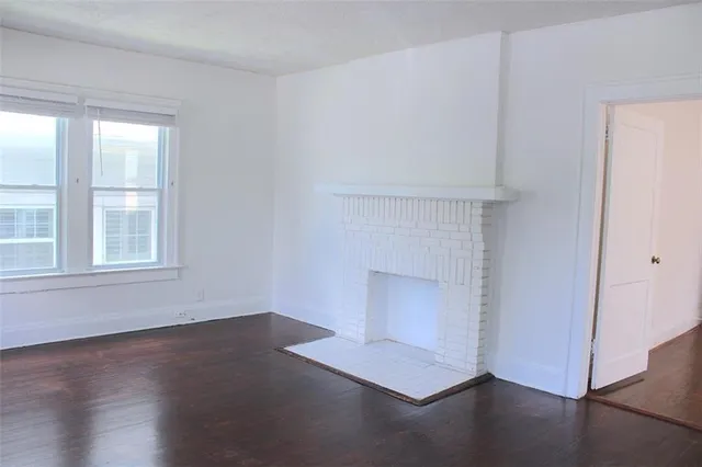 an empty room with wooden floor cabinet and windows