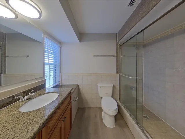 a bathroom with a granite countertop sink toilet a mirror and shower