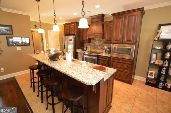 300 Grand Reserve Way Kathleen, GA 31047 - Photo 8 of 24 a kitchen with stainless steel appliances kitchen island granite countertop a table chairs and a refrigerator