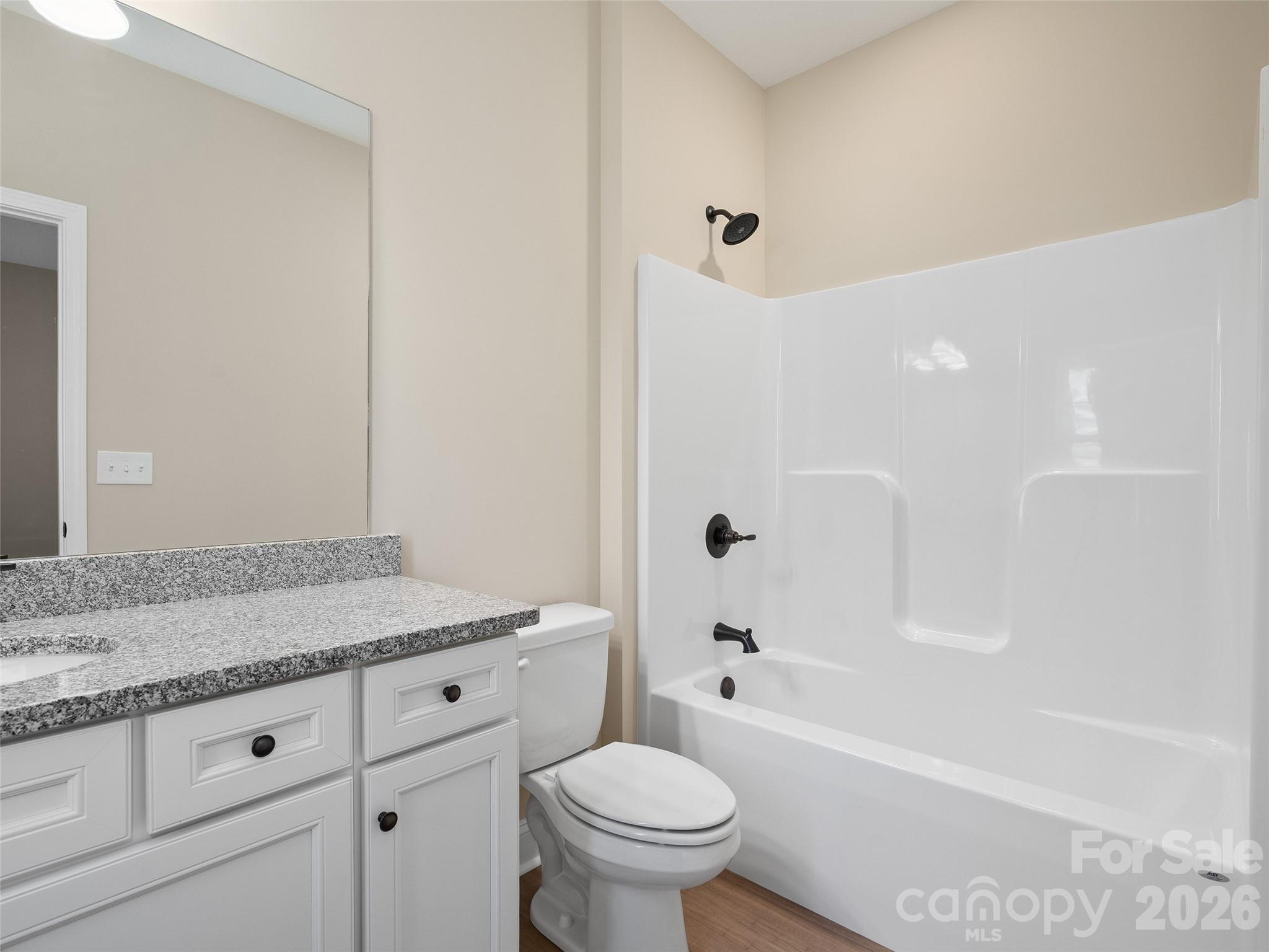 373 Barefoot Ridge Clyde, NC 28721 - Photo 21 of 30 a bathroom with a granite countertop toilet a sink and a bathtub