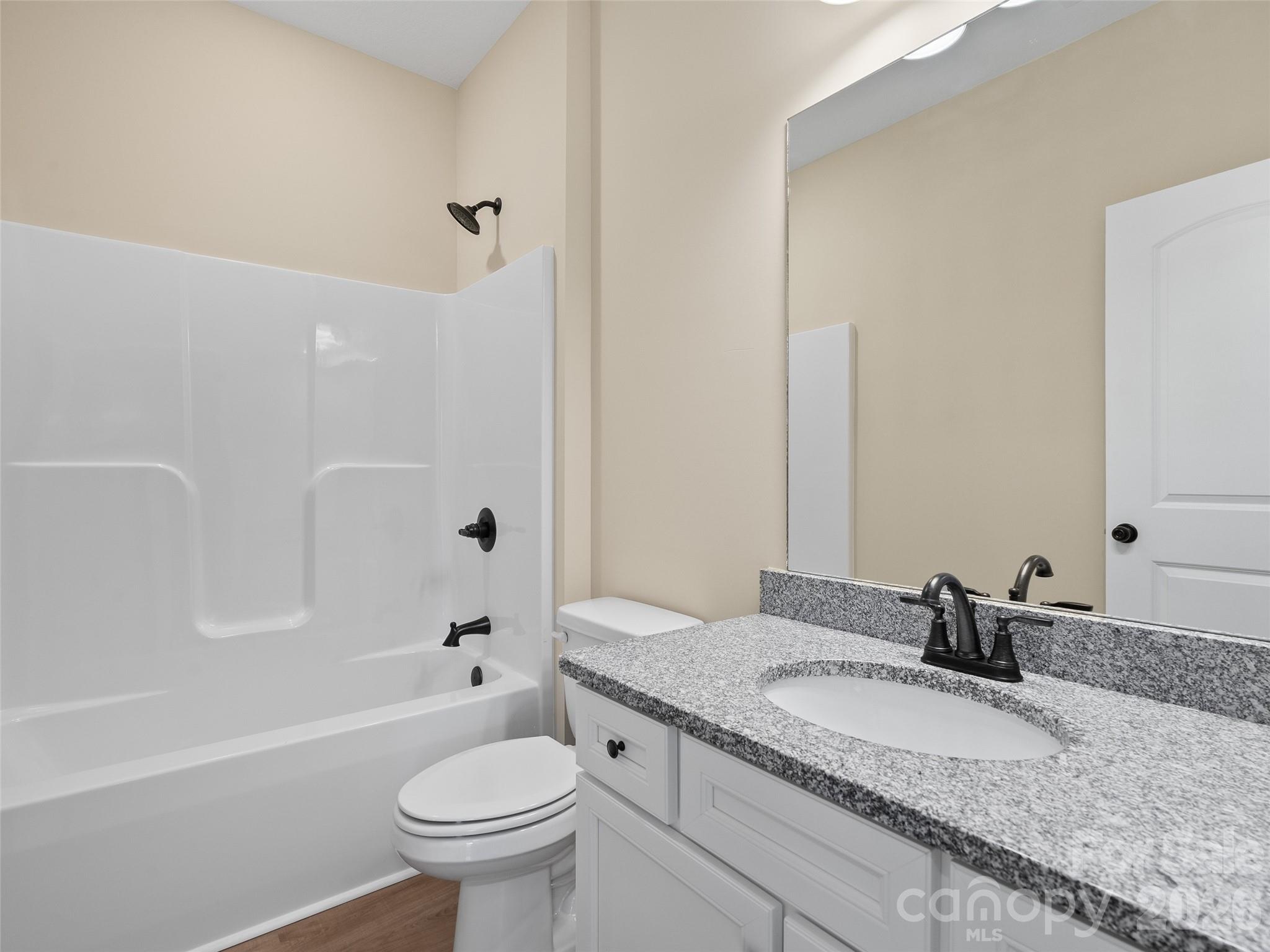 373 Barefoot Ridge Clyde, NC 28721 - Photo 24 of 30 a bathroom with a granite countertop sink a toilet and a large mirror