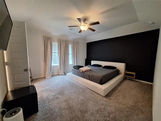 a bedroom with a bed and a flat tv screen on the dresser