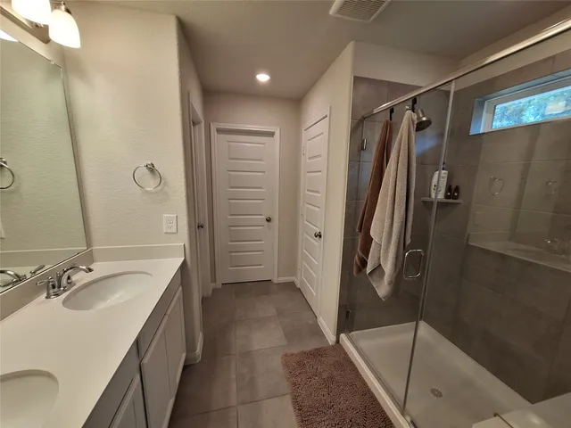 a bathroom with a granite countertop sink a mirror and shower