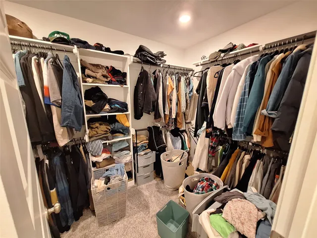 a view of walk in closet with clothes and shoes