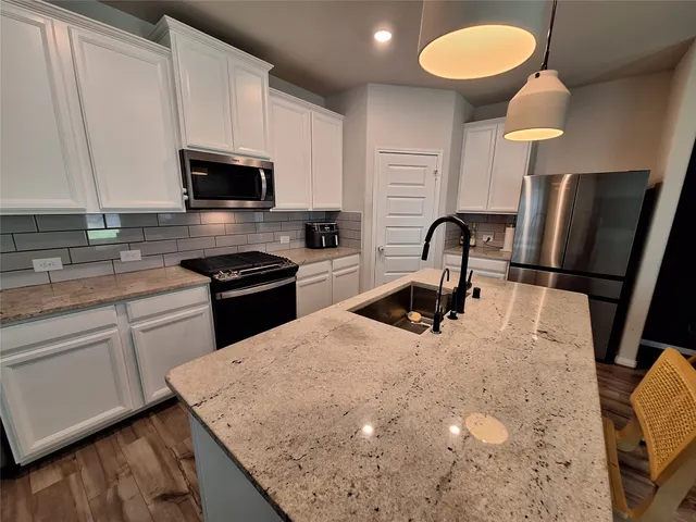 a kitchen with stainless steel appliances granite countertop a sink a stove and a refrigerator