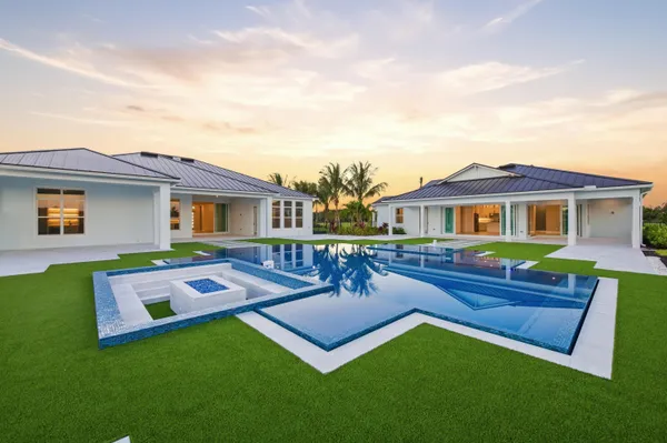 a view of a house with a big yard couches and large trees