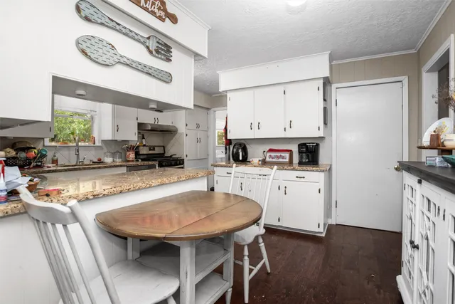 a kitchen with stainless steel appliances granite countertop a table chairs stove and cabinets